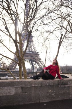 Şık bir kadın Paris 'te kayalık bir çıkıntıda uzanır, huzurlu bir günde Eyfel Kulesi' nin manzarasının tadını çıkarır.. 