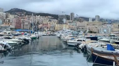 03.18.2025 Monaco, Fransa Lüks yatlar ve botlar yağmurlu bir günde Monacos limanına demirledi. Yüksek binalar ve sisli dağlar dramatik ve atmosferik bir zemin oluşturdu.