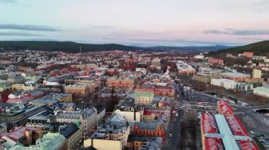 İsveç 'in Sundsvall kentinin 360 derecelik hava manzarası canlı renkli çatılar, kentsel yerleşim ve yumuşak gün ışığı altında manzaralı bir çevre manzarası sergiliyor..
