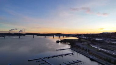 Sundsvall, İsveç 11.29.2024 Günbatımı Marina 'nın sakin sularını, yüzen limanları, bir köprüyü ve arka planda uzak endüstriyel dumanı gösteren görüntüleri.. 