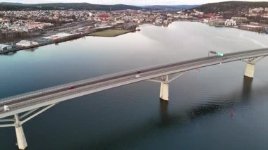 Gündoğumunda İsveç, Sundsvall 'ın hava manzarası sakin su üzerinde modern bir köprü, renkli bir şehir manzarası ve sakin şehir manzarasının üzerinde parlayan yumuşak pastel renkli bir gökyüzü gösteriyor.