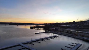 Sundsvall, İsveç 'in gündoğumunda sakin bir nehir, modern bir köprü, endüstriyel bir manzara ve su yüzeyine hafifçe yansıyan altın bir gökyüzü..