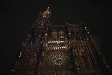Strasbourg Katedrali 'nin yukarıdan görünüşü Gotik kuleyi aydınlattı ve Alsace' de gece gökyüzüne doğru parlayan karmaşık gül penceresi. 