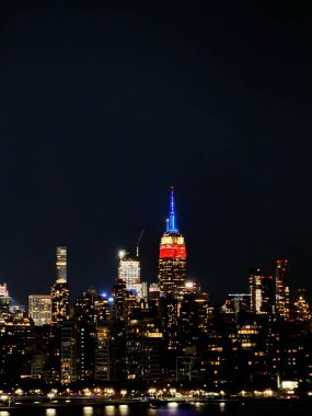 Empire State Binası New York şehrinin üzerinde kırmızı, mavi ve altın renginde parıldıyor.. 