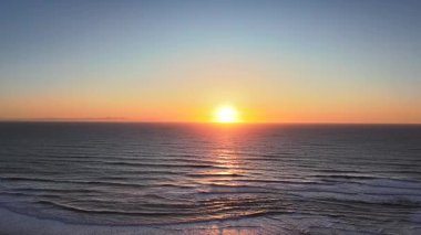 Altın günbatımında, kumulun arkasında alçaktan uçan ve kumları gizleyen ve güneşi batıran bir hava aracı videosu. Sıcak ışık ve sakin doğal manzarayla sinematik ve barışçıl bir gösteri.. 