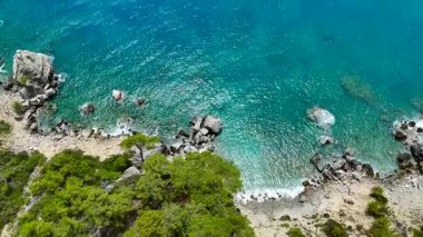 Temiz turkuaz suların havadan görünüşü engebeli Akdeniz kıyılarıyla kesişiyor. Deniz yüzeyindeki ışık parlaklığı huzurlu ve canlı bir kıyı manzarası yaratıyor. Seyahat görselleri için ideal.. 