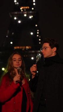 Romantik bir çift, Paris 'te özel bir anın tadını çıkarırken, gece ışıldayan Eyfel Kulesi' nin altında kadeh kaldırır..