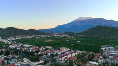 Antalya 'daki Taurus Dağları' nın altındaki yeşil tarım arazilerine ve orman tepelerine kurulmuş sakin bir kasabanın hava manzarası..