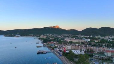 Sabahın erken saatlerinde Antalya 'da yeşil tepeler, uzak köyler ve görkemli dağlarla çevrili renkli bir tatil köyünün insansız hava aracı görüntüsü.. 