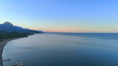Antalya 'nın sakin deniz manzarası, kıyı rıhtımları, ve uzak tepeleri olan liman kasabası gün doğumunda yumuşak sabah ışığı altında.. 