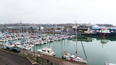 Boulogne. Fransa 03.28.2025 Arka planda eskrim ve sanayi binalarıyla çevrili yelkenli ve yatlarla dolu bir marina manzarası. 