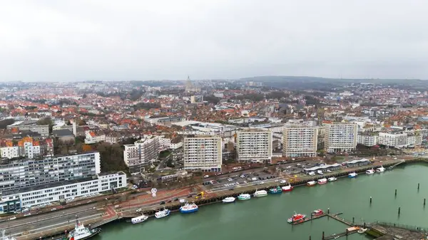 Boulogne. Fransa 03.28.2025 Boulogne-sur-Mer insansız hava aracı görüntüsü deniz kenarındaki binaları, demirlemiş tekneleri ve şehrin üzerinde yükselen tarihi bazilikayı gösteriyor.. 