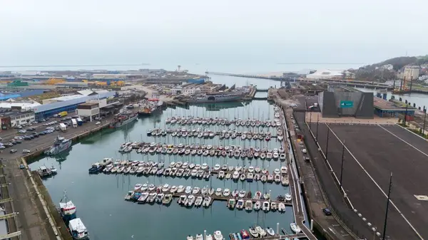 Boulogne. Fransa 03.28.2025 Deniz kenarındaki bir sanayi limanı ve kentsel altyapının yanında bulunan teknelerle dolu bir marinanın yüksek açılı fotoğrafı.. 