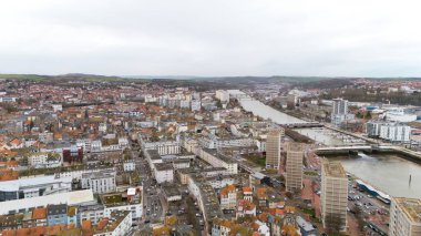 Boulogne. Fransa 03.28.2025 İHA görüntüsü nehir boyunca bir şehir manzarası yakalar, konut alanları, modern yüksek binalar, marinalar ve kırsal alanların ötesini gösterir.. 
