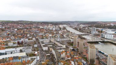 Boulogne. Fransa 03.28.2025 İHA görüntüsü nehir boyunca bir şehir manzarası yakalar, konut alanları, modern yüksek binalar, marinalar ve kırsal alanların ötesini gösterir.. 