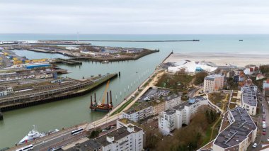 Boulogne. Fransa 03.28.2025 Bir sahil limanının robot resmi İnşaat mavnası, sahil gezinti güvertesi, modern binalar, ve rıhtıma yakın yerleşim alanı. 