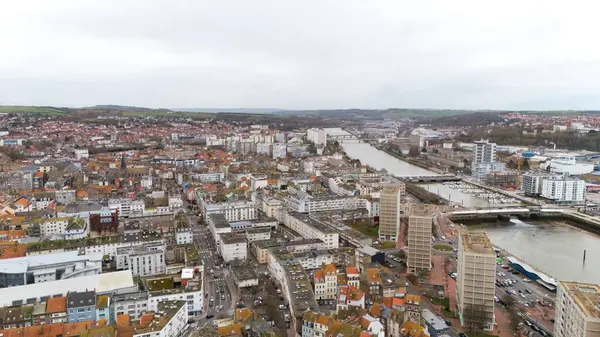 Boulogne. Fransa 03.28.2025 İHA görüntüsü nehir boyunca bir şehir manzarası yakalar, konut alanları, modern yüksek binalar, marinalar ve kırsal alanların ötesini gösterir.. 