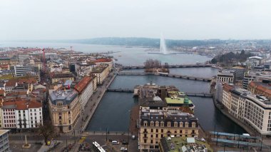 Cenevre, İsviçre 04.11.2025 Bir Avrupa göl kenti görüntüsü Köprüler, eski binalar, ve bulutlu bir kış gökyüzünün altındaki ünlü su çeşmesi.