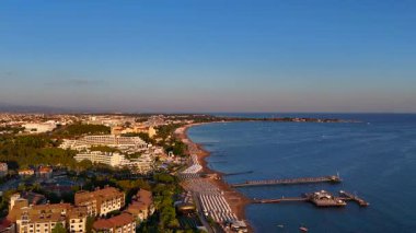 İHA görüntüleri kıyı şeridinden açık denize ulaşarak, uzak rıhtımlar ve teknelerle ufka uzanan sakin mavi suyu ortaya çıkarıyor. Sinema geçişleri ve dingin ruh halleri için ideal..