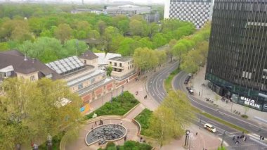 Berlin, Almanya 04.20.2025 Geniş açılı kamera hareketi, yollar, binalar, yeşillikler ve baharda Berlin Hayvanat Bahçesi yakınlarında bir heykel havuzu gösteriyor.. 