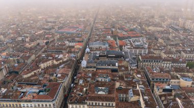 Bordeaux France 'ın insansız hava aracı görüntüsü kırmızı kiremitli çatıları dar sokakları ve tarihi şehir merkezinde sisli atmosferi gösteriyor. 