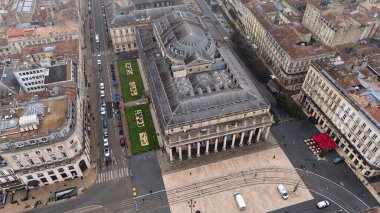 Büyük Bordeaux Tiyatrosu 'nun insansız hava aracı görüntüsü klasik mimariyi, tramvay raylarını ve bulutlu gökyüzünün altındaki yakın kafeleri gösteriyor.