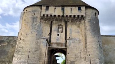 Fransa 'nın Caen şehrinde çift yuvarlak kuleleri, kapı kolları ve asılı zincirleri olan bir ortaçağ kalesinin taş giriş kapısı..