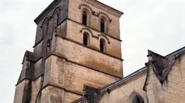 Çan kulesini kapatın. Gökyüzünün altında kavisli pencereli ve yıpranmış taşlı Romanca mimariyi gösterin.