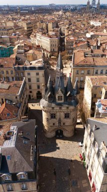 Bordeaux 'daki Porte Cailhau' nun insansız hava aracı görüntüleri simetrik perspektifle tarihi taş kuleyi, çatıları ve güneşli gün ışığında dar sokakları gösteriyor..