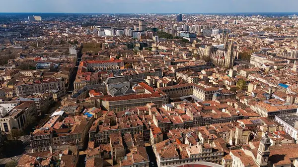 Bordeaux şehrinin insansız hava aracı görüntüsü tarihi çatılar, modern binalar ve güneşli bir şehir manzarasındaki katedrali gösteriyor..