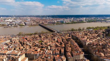 Pont de Pierre 'in Bordeaux' da çekilen robot resmi Garonne Nehri 'ni geçerken, çevresindeki çatılar ve şehir manzarası güneşli bir günde.