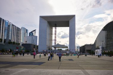 Büyük Kemer ve modern ofis binaları bulutlu bir günde, Paris, Fransa 06.01.2025 'te arka planda iken, La Defense iş bölgesinde meydanda yürüyen insanların geniş görüşü