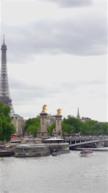 Paris, Fransa 06.07.2025 Seine Nehri 'nin panoramik manzarası Pont Alexandre III yakınlarında seyreden tekneler, süslü köprüde altın heykeller ve arka planda yükselen Eyfel Kulesi.