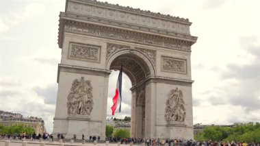 Paris, Fransa 06.08.2025 Turistler Zafer Takı 'nın tabanında toplandı. Bulutlu bir günde tarihi anıtın altında ulusal üç renkli bayrak dalgalandı..