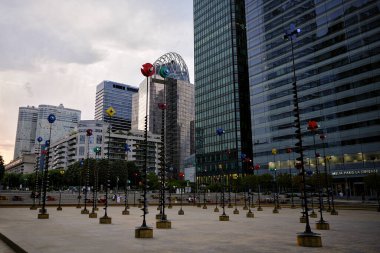 Heykeller ve modern gökdelenler günbatımında La Defense Paris 'te halka açık bir meydanın etrafını sarar.