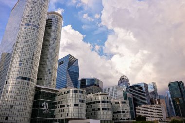 La Defense Paris 'te cam gökdelenler ve ofis kuleleri dramatik gökyüzü altında dış görünüş ve iş bölgesinde belirgin mimari yansımalarla