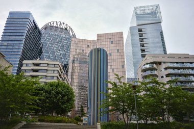 La Defense Paris 'te modern cam kulelerin önünde renkli bir heykel duruyor. Ağaçların merdivenleri ve yumuşak bulutlu gökyüzünün altındaki konut binaları var.