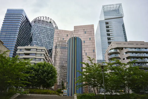 La Defense Paris 'te modern cam kulelerin önünde renkli bir heykel duruyor. Ağaçların merdivenleri ve yumuşak bulutlu gökyüzünün altındaki konut binaları var.