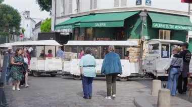 Yolcularla dolu mini turist treni Paris 'te bir kaldırım taşı caddesinde Galerie Butte Montmartre' ın yanından geçiyor. Sadece editörler kullanır. Haziran 2025.