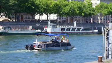 Küçük bir yatta dans eden genç kadınlar güneşli bir yaz gününde arka planda rıhtımlı tekneler ve klasik mimariyle Paris 'te Seine Nehri boyunca seyahat ediyorlar. Sadece editörler kullanır. Fotoğraf: 14 Haziran 2025.