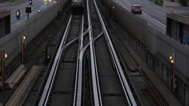 Metro treni Paris 'te yol trafiğiyle çevrili yüksek raylara geliyor. Ön camdan görünen yolcular ve kavşakta kıvrılan raylar var. 15 Haziran 2025 'te yakalandı.