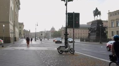 26 Haziran 2025 'te Berlin' in merkezinde meydana gelen ani bir fırtına sırasında yürüyen ve bisiklete binen insanlar Unter den Linden Bulvarı yakınlarında güçlü rüzgar ve uçan enkaz parçaları ve binicilik heykeli ile 