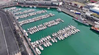 Boulogne sur Mer marinasının bulutlu gökyüzünün altında turkuaz su altında sıralanmış yatları ve tekneleri olan dikey yayın kamerası görüntüleri, 10 Temmuz 2025 'te Kuzey Fransa' da liman altyapısını gösteriyor.