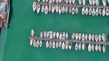 Zümrüt suyu ve Fransa 'nın Boulogne sur Mer kentindeki rıhtımların geometrik yerleşimi olan bir marinaya kenetlenmiş beyaz yatların sinematik dikey hava görüntüleri.