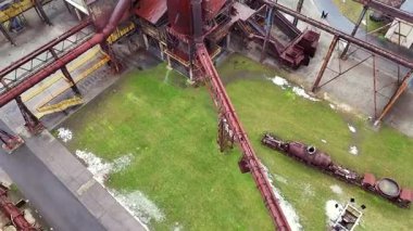 Birbirine bağlı boru hatlarının hava aracı görüntüsü ve eski endüstriyel bir komplekste görünür yürüyüş yolları, merdivenleri ve altyapısı olan paslı bir fırın. 