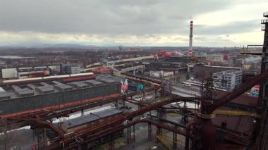 3 Şubat 2025 'te Çek Cumhuriyeti' nin Dolni Vitkovice kentinin havadan görünüşü, paslanmış endüstriyel boru hatları, toplu taşıma hatları, binalar ve dramatik gökyüzünün altında tüten bir bacayla