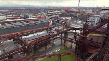 3 Şubat 2025 tarihinde Çek Cumhuriyeti 'nin Ostrava kentindeki Dolni Vitkovice kompleksindeki çimenli bir arazide, boru hatları ve çelik fabrikalarıyla çevrili eski bir demiryolu aracının insansız hava aracı görüntüsü hala duruyor.