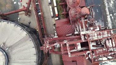 Paslı çelik tankların ve çevresi otobüsler, arabalar ve park alanları da dahil olmak üzere endüstriyel boru sisteminin tepeden aşağı hava görüntüsü. 
