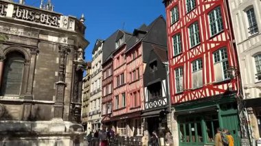 Fransa Rouen 'daki tarihi taş şapel duvarı 3 Nisan 2025' te gotik oymalar ve kavisli pencereler ile renkli yarı ahşap evler ve sokak kafelerine bakıyor. 