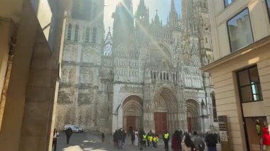 Fransa 'daki Rouen Katedrali' nin önü 3 Nisan 2025 'te turist ve okul çocukları meydanda toplanırken, gotik kulelerden güneş ışığı akıyor. 